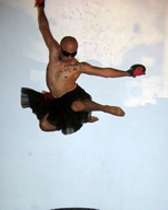 A shirtless man leaping in the air with a sky-blue background